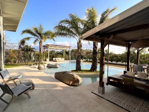 a swimming pool with chairs and palm trees in a house at The Castle Uluwatu - Ocean View Luxury villa in Uluwatu