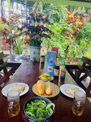 a wooden table with plates of food and drinks at Cát Tiên Riverside in Tân Phú
