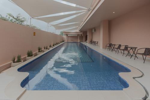 a swimming pool in a building with tables and chairs at Anaya Azana Boutique Hotel Tawangmangu in Tawangmangu
