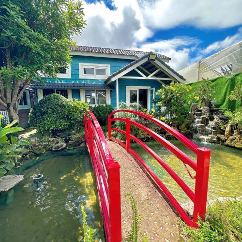 a red bridge over a pond in front of a house at Homestay Đà Lạt - The November Stay in Da Thanh