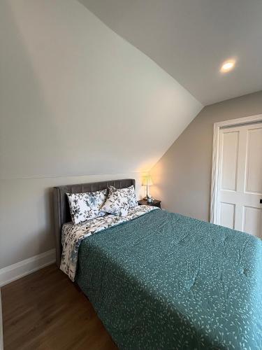 a bedroom with a bed with a green comforter at Downtown Huntsville Gem in Muskoka in Huntsville