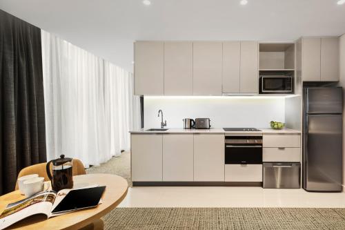 a kitchen with white cabinets and a wooden table at Quest St Leonards in Sydney