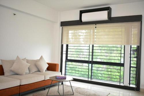 a living room with a couch and a large window at Spring Hill Hotel and Service Apartments in Dhaka