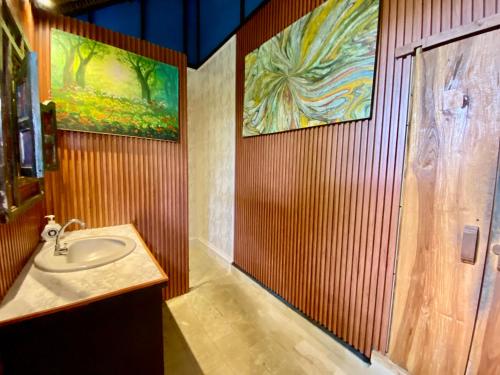 a bathroom with a sink and paintings on the wall at Blind Dog Inn in Sanur