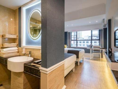 a bedroom with a bed and a sink and a mirror at Ming Yang Hotel in Haikou