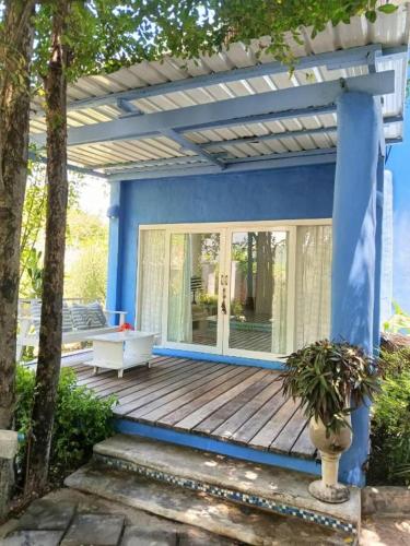 a blue house with a wooden deck with a couch at Brassiere Beach Hotel in Baanphakrimlay 