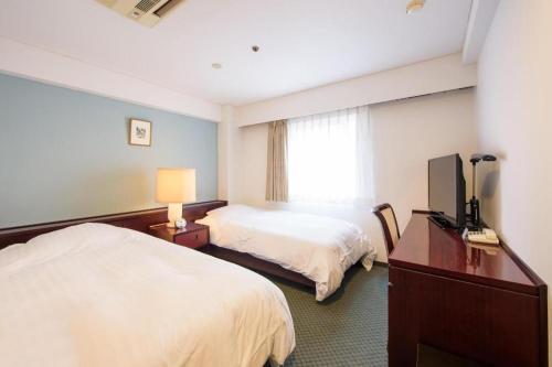 a hotel room with two beds and a television at Oita Century Hotel in Oita