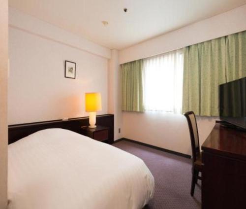 a hotel room with a bed and a television at Oita Century Hotel in Oita