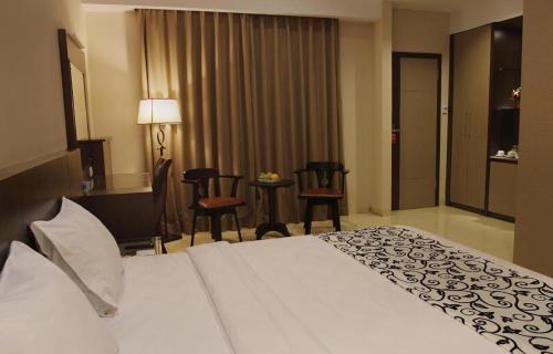 a hotel room with a white bed and chairs at Mega Permata Hotel in Padangsidimpuan