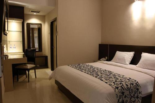 a hotel room with a large bed and a table at Mega Permata Hotel in Padangsidimpuan