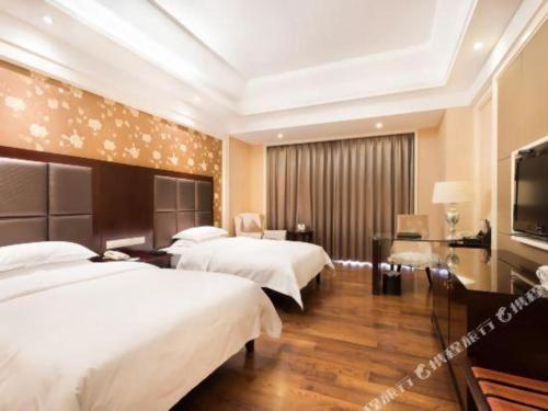 a hotel room with two beds and a flat screen tv at Jinjiang Grandlink Hotel in Quanzhou