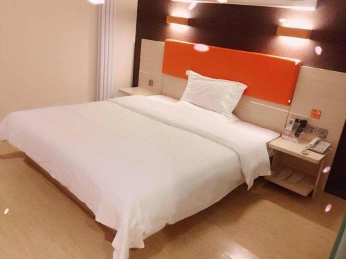 a bedroom with a large white bed with an orange headboard at 7 Days Premium Dezhou Qingyun Nanhuan Building Materials Market in Dezhou