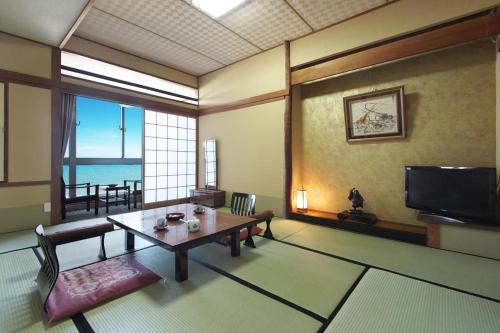 a living room with a table and a television at Futami Onsen Hotel Seikai in Ise