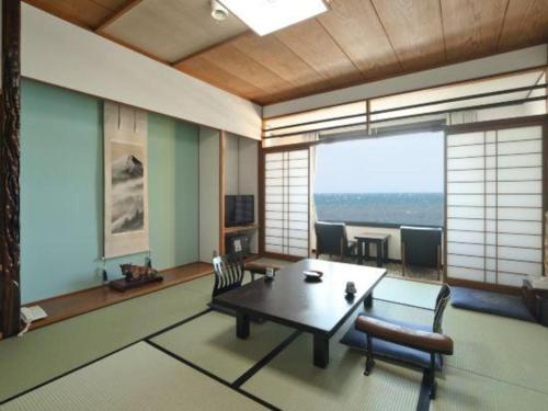 a living room with a table and chairs and a large window at Futami Onsen Hotel Seikai in Ise