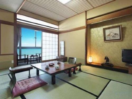 a living room with a table and a view of the ocean at Futami Onsen Hotel Seikai in Ise