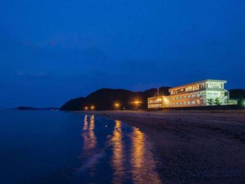 a building on the shore of a beach at night at Futami Onsen Hotel Seikai in Ise