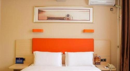 a bed with an orange headboard and a picture above it at 7 Days Premium Beijing Dabaotai Metro Station Luhua Road in Beijing