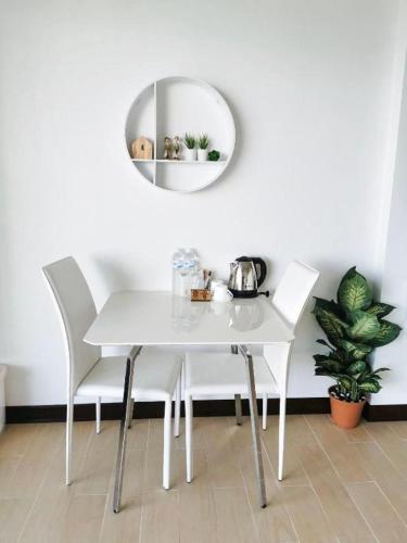 a white dining room table with white chairs and a mirror at C View Home in Nan