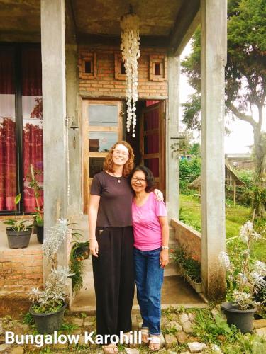 two women standing in front of a house at Bungalow Karo Hill in Berastagi