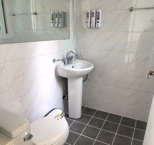 a white bathroom with a toilet and a sink at Humming stay in Seoul
