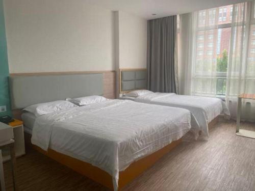 a hotel room with two beds and a window at 7Days Inn Tianjin Airport NO.1 Bridge Branch in Tianjin