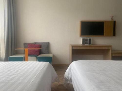 a hotel room with two beds and a television at 7Days Inn Tianjin Airport NO.1 Bridge Branch in Tianjin