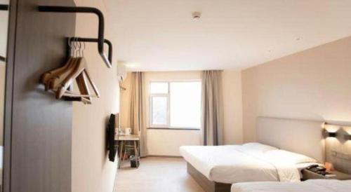 ein Hotelzimmer mit zwei Betten und einem Fenster in der Unterkunft 7 Days Inn Tianjin Binhai Passenger Station Huabei Ceramics in Binhai