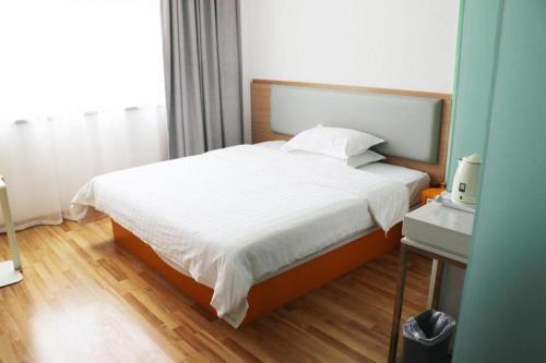 a bedroom with a large bed with white sheets at 7Days Inn Tianjin Airport NO.1 Bridge Branch in Tianjin