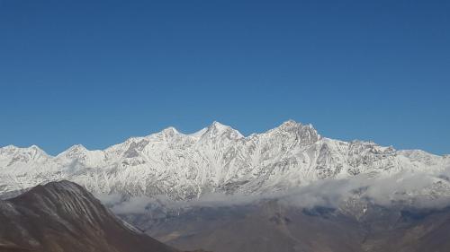 a snow covered mountain range with a reflection in the water at Hotel Grand Shambala in Muktināth