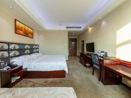 a bedroom with a bed and a desk and a television at Li An Hotel Shantou Xiashan Central Bus Station Branch in Shantou
