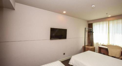 a bedroom with two beds and a tv on the wall at Jinjiang Inn Style Shijiazhuang Zhongshan Xi Road Yuxi Park in Shijiazhuang
