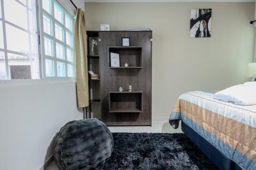 a bedroom with a bed and a chair next to a window at BnB rooms in downtown Cancun- Casa Sunshine Cancun in Cancún
