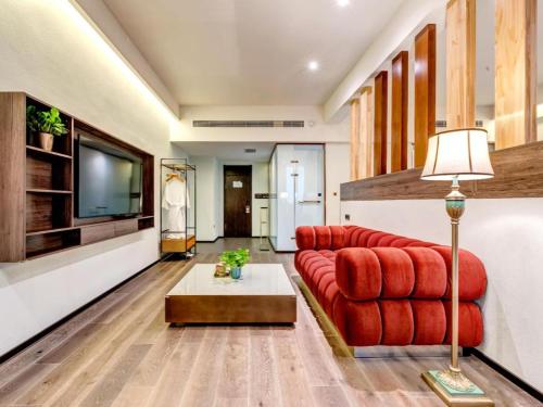 a living room with a red couch and a tv at James Joyce Coffetel·Anyang Text Museum in Anyang