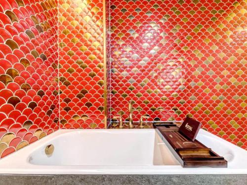 a bathroom with a bath tub with a mosaic wall at James Joyce Coffetel·Anyang Text Museum in Anyang
