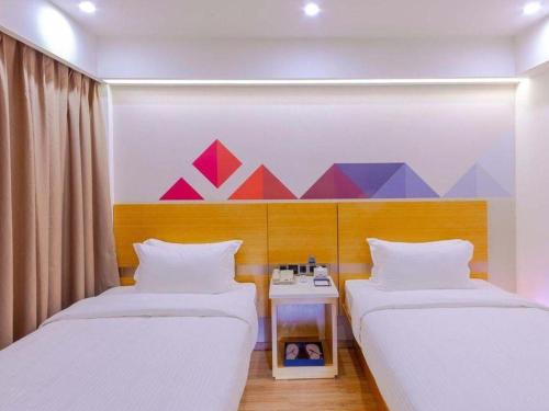 two beds in a room with a painting on the wall at Borrman Hotel Zhanjiang Shimao Building High-speed Railway Station in Zhanjiang