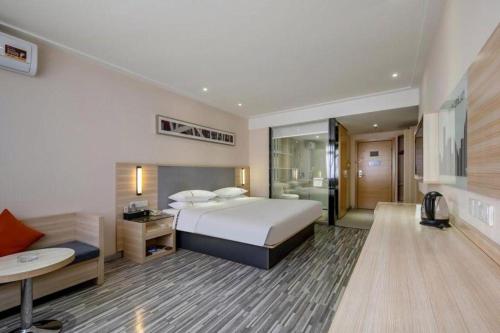 une grande chambre d'hôtel avec un lit et un bureau dans l'établissement JTOUR Inn Yizhou Hechi College Pedestrian Street, à Qingyuan