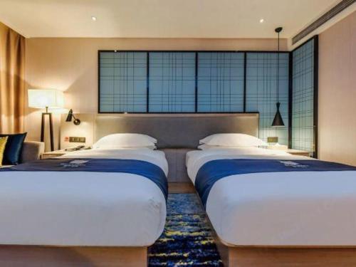 two beds in a bedroom with a large window at Echarm Hotel Anshun High-speed Railway Station Jichang Road in Anshun
