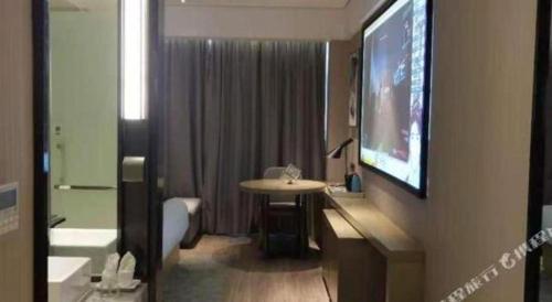 a bathroom with a tv on a wall with a sink at Echarm Hotel Nanning Chaoyang Square River View in Nanning