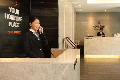 a woman talking on a cell phone at a desk at Hotel Skypark Myeongdong 2 in Seoul