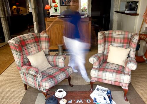 a person walking through a living room with two chairs at Le Petit Hôtel des Hortensias in La Trinité-sur-Mer
