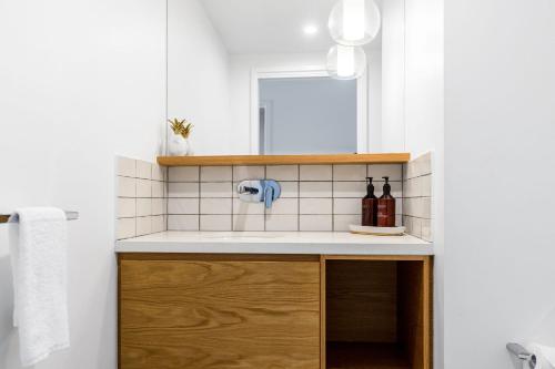 a bathroom with a sink and a mirror at Fat Frog Beach Houses in Byron Bay