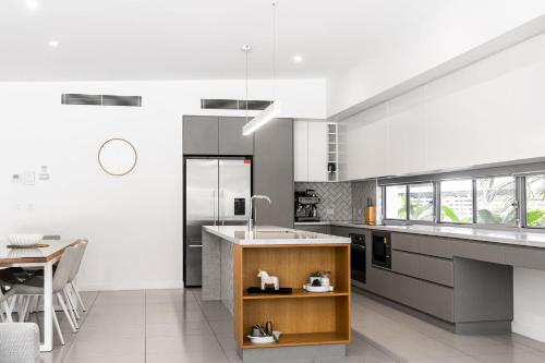 a large kitchen with a counter and a table at Fat Frog Beach Houses in Byron Bay