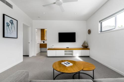 a living room with a table and a tv at Fat Frog Beach Houses in Byron Bay