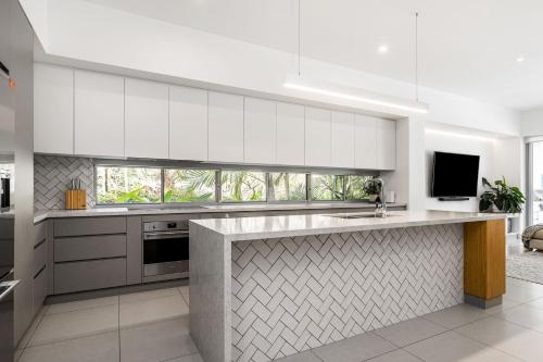 a kitchen with white cabinets and a counter top at Fat Frog Beach Houses in Byron Bay