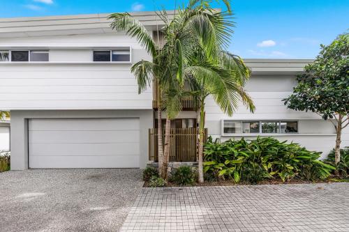 a white house with palm trees in front of it at Fat Frog Beach Houses in Byron Bay