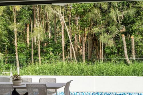 a room with a table and chairs and trees at Fat Frog Beach Houses in Byron Bay
