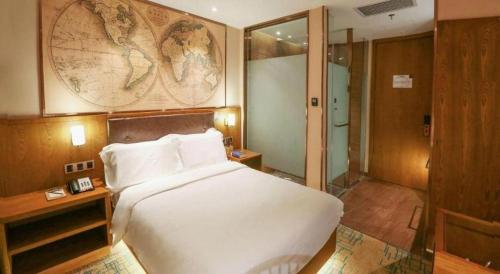 a bedroom with a large white bed and a map on the wall at James Joyce Coffetel Changchun People's Square in Changchun