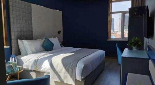 a bedroom with a large bed with a blue wall at LANO Hotel Shandong Qingdao Jimo District Baolong Square in Qingdao
