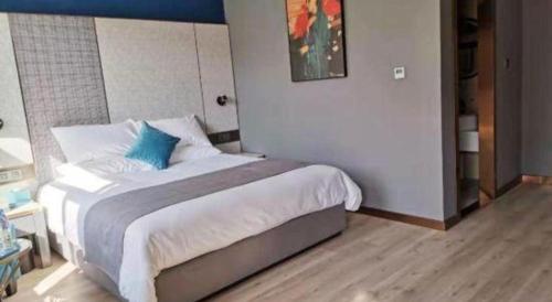 a bedroom with a large bed with a blue pillow at LANO Hotel Shandong Qingdao Jimo District Baolong Square in Qingdao