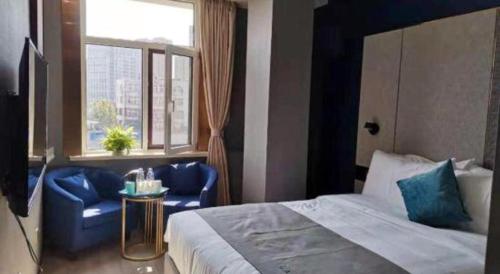 a bedroom with a bed and two blue chairs and a window at LANO Hotel Shandong Qingdao Jimo District Baolong Square in Qingdao